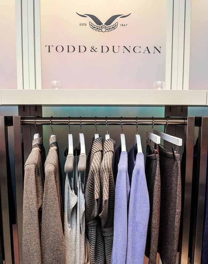 The Todd & Duncan name and logo on the wall above a rack of clothes